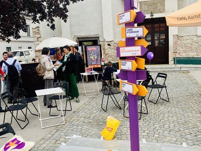 Stadtteilcafé Liesing Selbst gestalteter Wegweiser auf einem Platz.