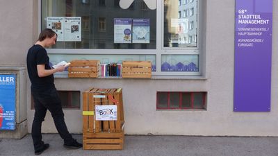 GB*Mitarbeiter schmökert in den Büchertauschkisten vor dem GB*Stadtteilmanagement-Lokal