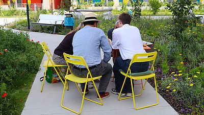 Mehrere Menschen sitzen im Freien an einem Tisch und unterhalten sich.