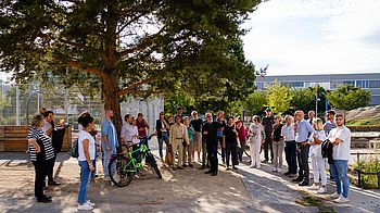 Eine Gruppe von Menschen versammelt sich unter einem Baum - anlässlich einer geführten Stadtteiltour der GB*